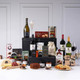 The Taste of Ireland Gourmet Hamper/ A display of gourmet food and beverages arranged on a table. The assortment includes two bottles of red wine, one bottle of prosecco, jars of preserves, assorted cookies, cheese, and a fruitcake. Several boxes with snacks are featured prominently alongside wine glasses filled with contrasting beverages. The backdrop is neutral with subtle decorative elements. The Taste of Ireland Gourmet Hamper/ A display of gourmet food and beverages arranged on a table. The assortment includes two bottles of red wine, one bottle of prosecco, jars of preserves, assorted cookies, cheese, and a fruitcake. Several boxes with snacks are featured prominently alongside wine glasses filled with contrasting beverages. The backdrop is neutral with subtle decorative elements.